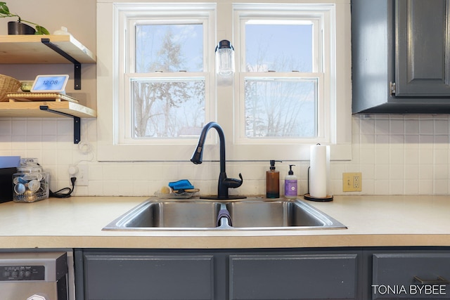 kitchen with gray cabinetry, washer / clothes dryer, a sink, light countertops, and tasteful backsplash