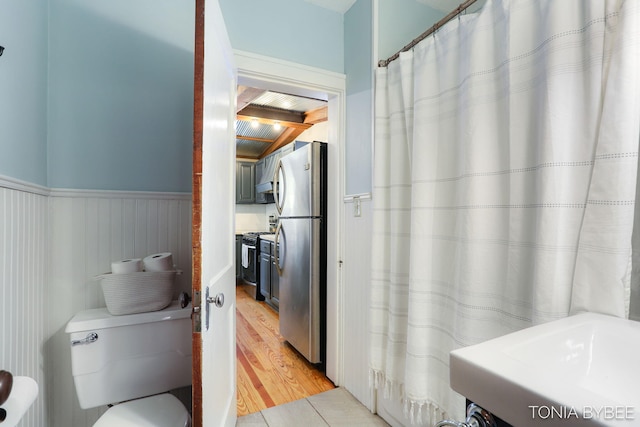 bathroom featuring wainscoting, wood finished floors, and toilet