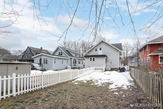 snow covered rear of property featuring fence private yard and a residential view