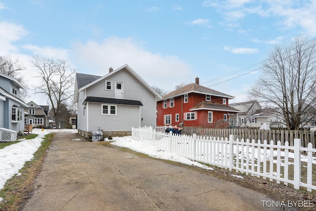 exterior space with a fenced front yard, a residential view, a chimney, and roof with shingles