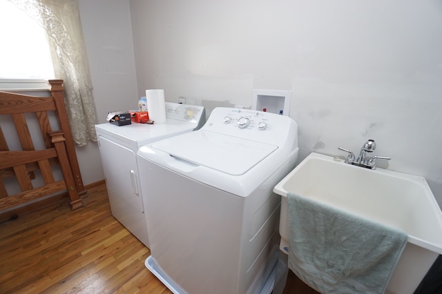 laundry room with light wood finished floors, washing machine and dryer, laundry area, and a sink