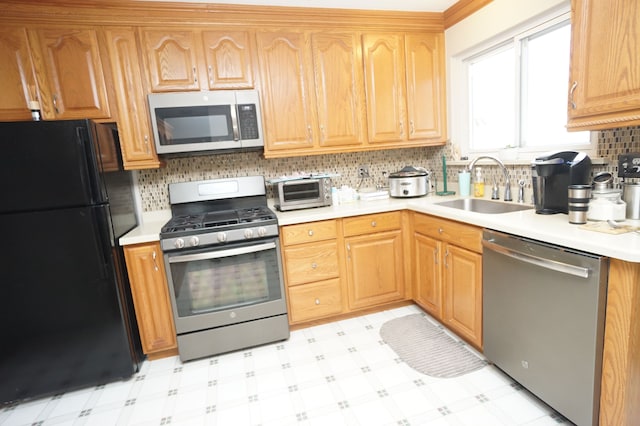 kitchen with appliances with stainless steel finishes, light countertops, a sink, and light floors