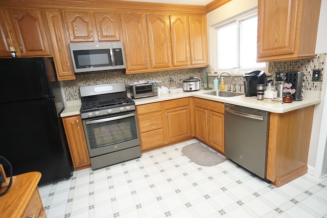 kitchen featuring light floors, appliances with stainless steel finishes, light countertops, and a sink