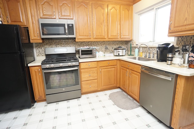 kitchen featuring light floors, appliances with stainless steel finishes, light countertops, and a sink