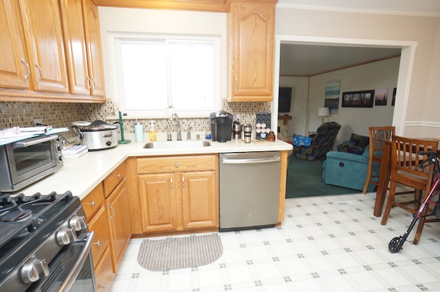 kitchen featuring a sink, light countertops, ornamental molding, appliances with stainless steel finishes, and light floors