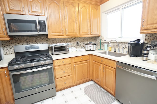 kitchen with a toaster, a sink, light countertops, appliances with stainless steel finishes, and light floors