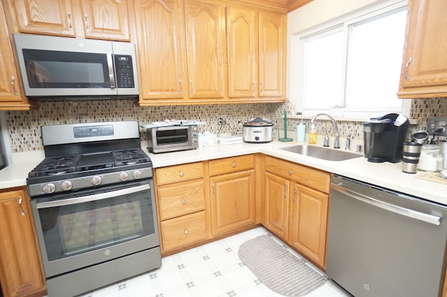 kitchen with a toaster, a sink, light countertops, appliances with stainless steel finishes, and light floors