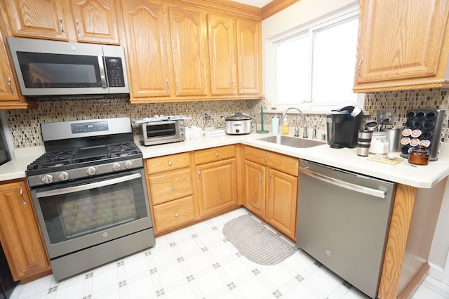 kitchen featuring a toaster, light floors, light countertops, appliances with stainless steel finishes, and a sink