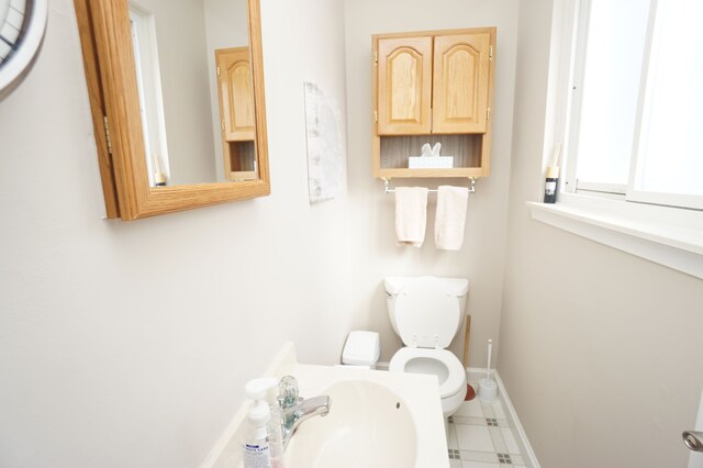 bathroom with baseboards, a sink, and toilet