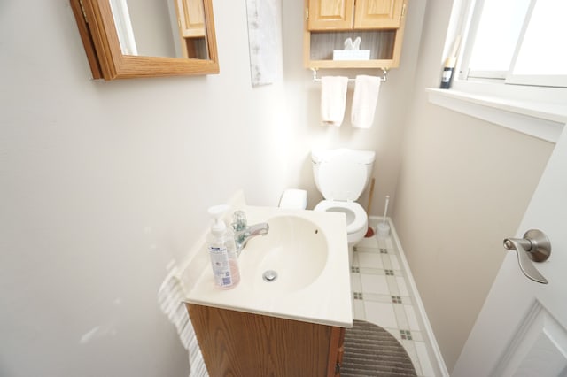 half bathroom featuring baseboards, vanity, and toilet