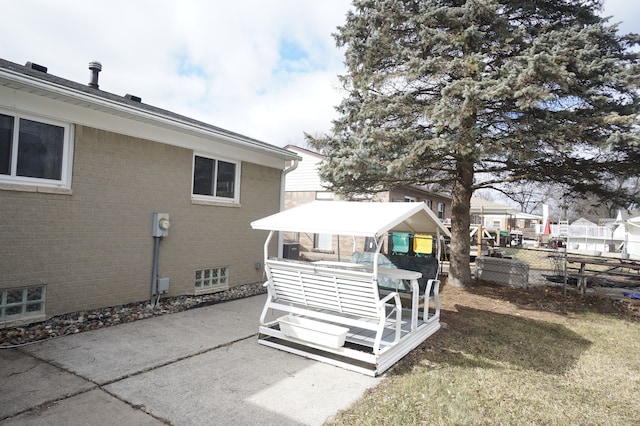 rear view of property featuring fence, a patio, and brick siding