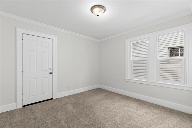 spare room featuring carpet floors, crown molding, and baseboards