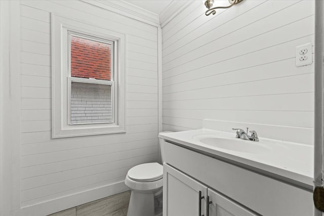 half bathroom featuring crown molding, vanity, toilet, and wood finished floors