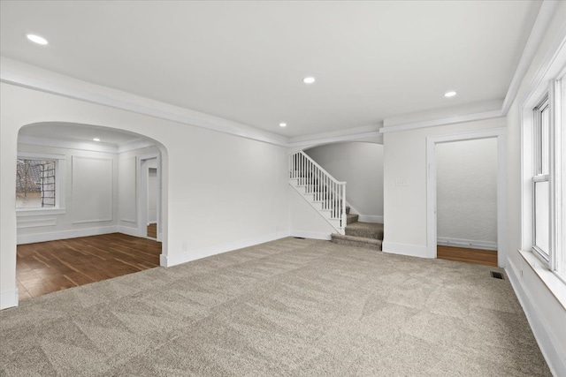 unfurnished room featuring arched walkways, carpet, stairs, and visible vents