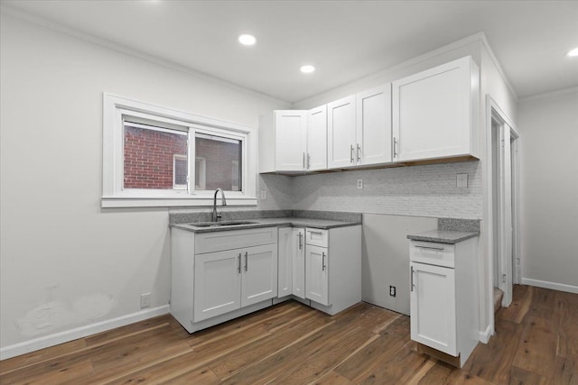 kitchen featuring dark wood-type flooring, baseboards, a sink, and decorative backsplash