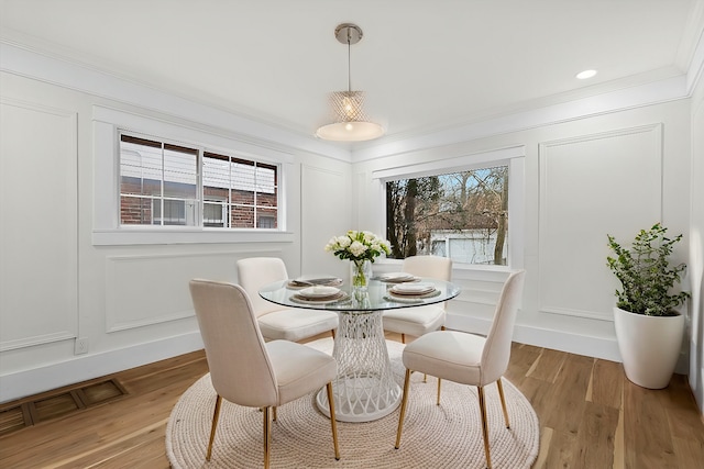 dining space with plenty of natural light, visible vents, a decorative wall, and light wood-style flooring