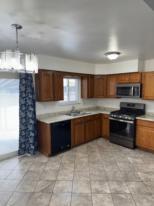 kitchen featuring stainless steel appliances, a sink, light countertops, and decorative light fixtures