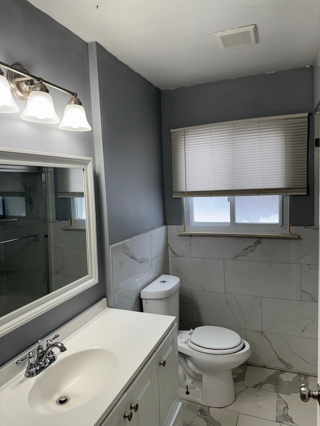 bathroom with visible vents, a shower, toilet, marble finish floor, and vanity