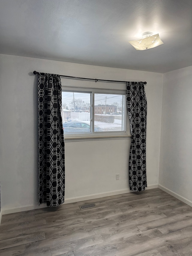 empty room with visible vents, baseboards, and wood finished floors