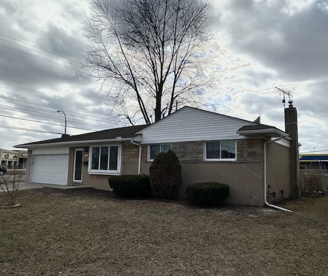 single story home with a garage, driveway, brick siding, a chimney, and a front yard