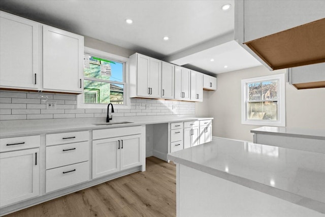 kitchen with recessed lighting, a sink, decorative backsplash, white cabinetry, and light wood-type flooring