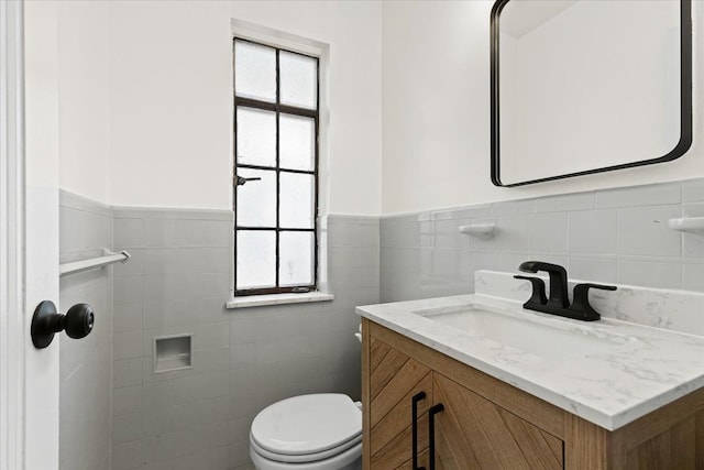 bathroom with wainscoting, a healthy amount of sunlight, toilet, and vanity