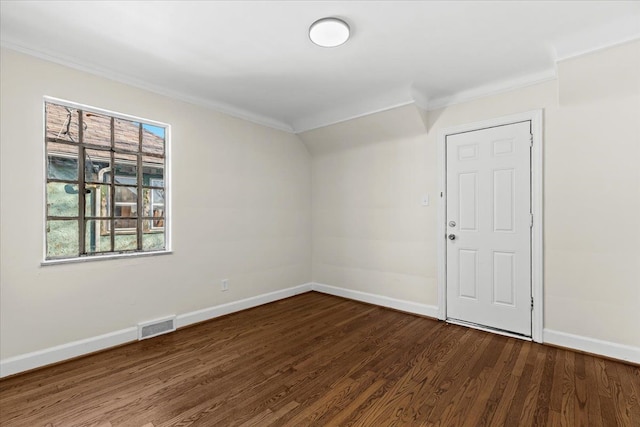 spare room featuring dark wood finished floors, visible vents, baseboards, and ornamental molding