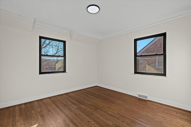 spare room with visible vents, baseboards, wood finished floors, and crown molding