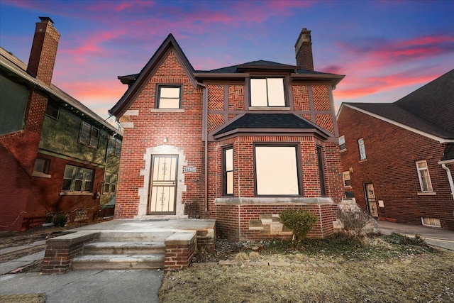 view of front of property featuring brick siding and a chimney