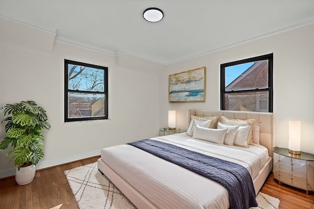 bedroom with baseboards, wood finished floors, and ornamental molding