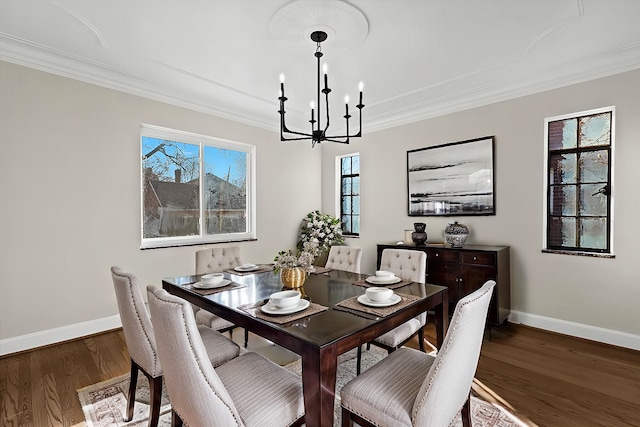 dining space featuring baseboards, an inviting chandelier, wood finished floors, and ornamental molding