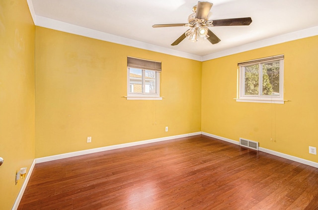 unfurnished room featuring wood finished floors, visible vents, and baseboards