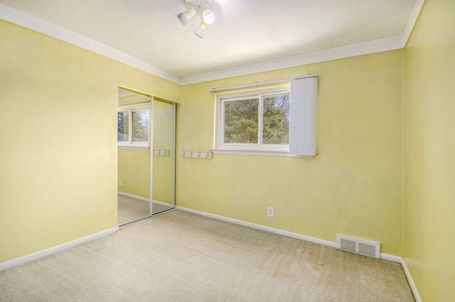 unfurnished bedroom with baseboards, multiple windows, visible vents, and carpet flooring