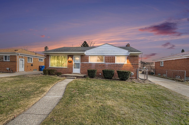 bungalow featuring a yard, brick siding, a chimney, and fence