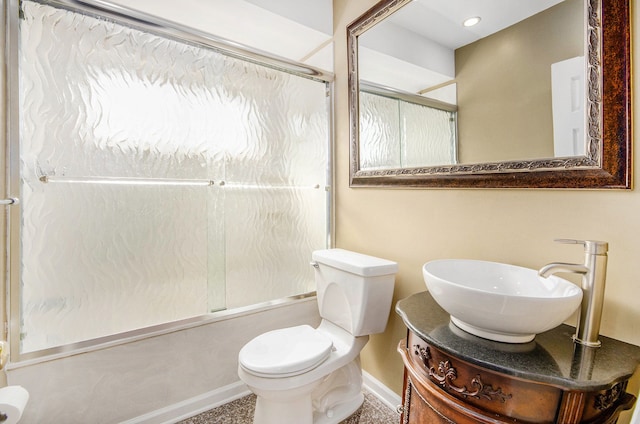 bathroom featuring toilet, bath / shower combo with glass door, vanity, and baseboards