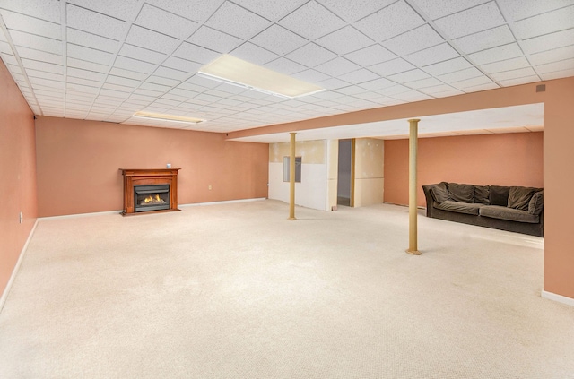 finished basement with a lit fireplace, baseboards, a drop ceiling, and carpet flooring