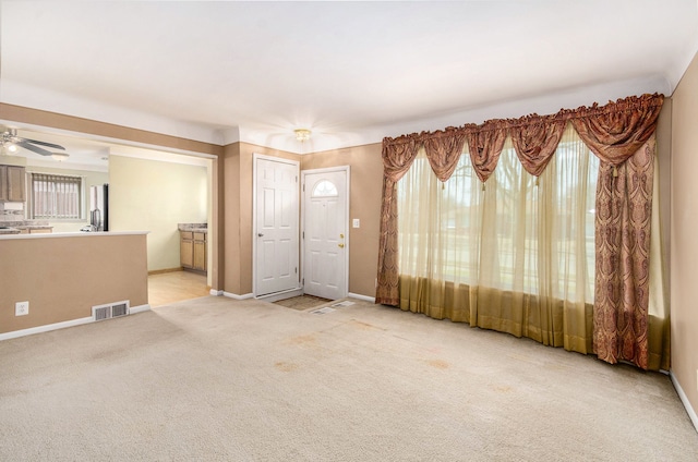 unfurnished living room featuring light carpet, baseboards, visible vents, and a healthy amount of sunlight