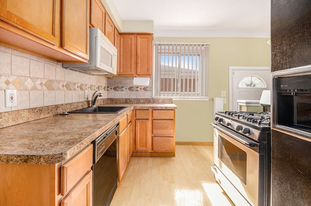 kitchen with stainless steel range with gas cooktop, decorative backsplash, a sink, light wood-type flooring, and dishwasher