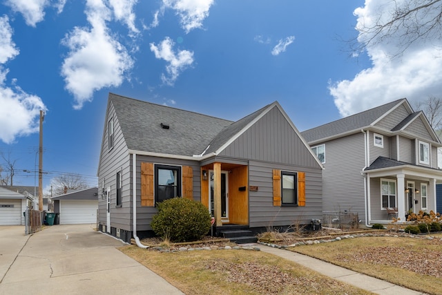 view of front of home featuring an outbuilding, board and batten siding, a detached garage, and roof with shingles