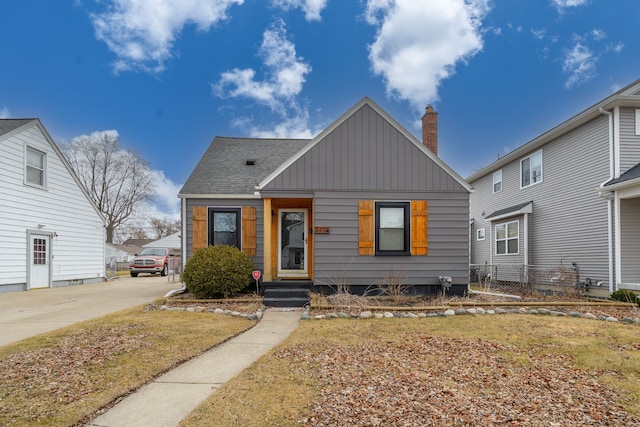 bungalow-style house featuring board and batten siding, a chimney, roof with shingles, and fence