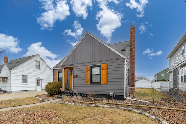 view of front of property with a shingled roof, fence, board and batten siding, and a chimney