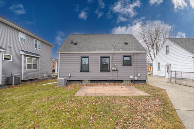 rear view of house with cooling unit, a lawn, roof with shingles, and fence