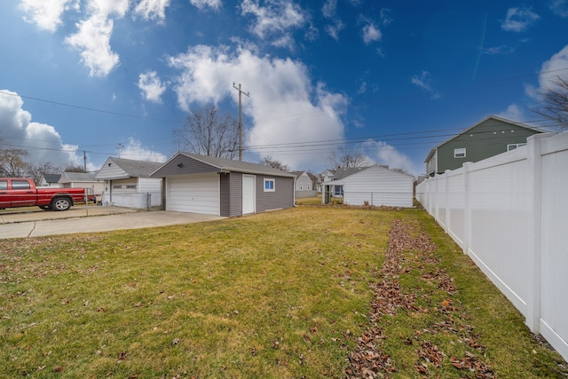 view of yard featuring a garage, an outbuilding, and fence