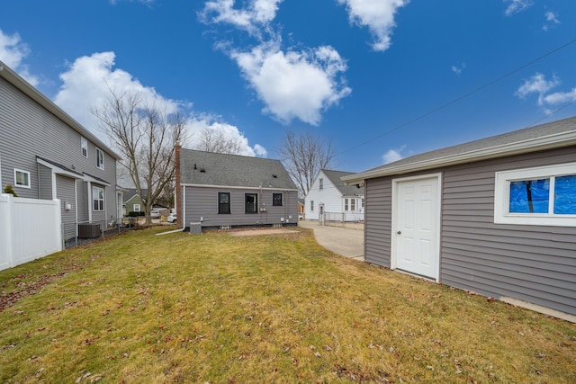 rear view of house with cooling unit, a yard, and fence