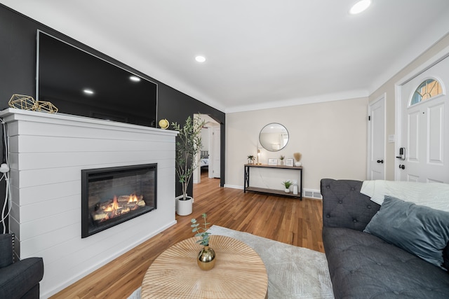 living area featuring visible vents, baseboards, recessed lighting, wood finished floors, and a glass covered fireplace