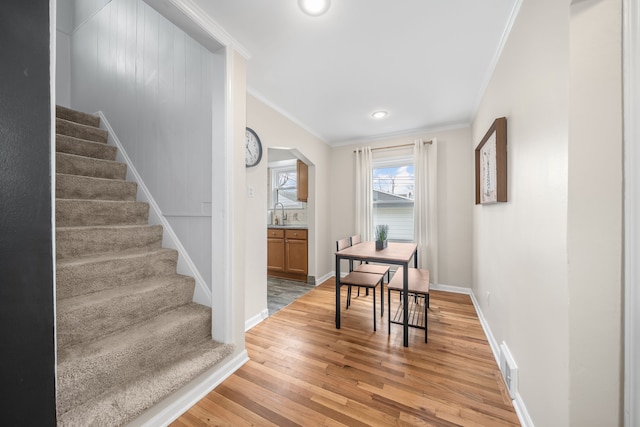 interior space with stairway, baseboards, light wood finished floors, arched walkways, and crown molding