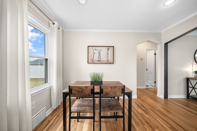 dining area featuring baseboards, visible vents, arched walkways, ornamental molding, and light wood-style floors