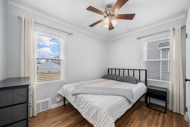 bedroom featuring visible vents, ornamental molding, baseboards, and wood finished floors