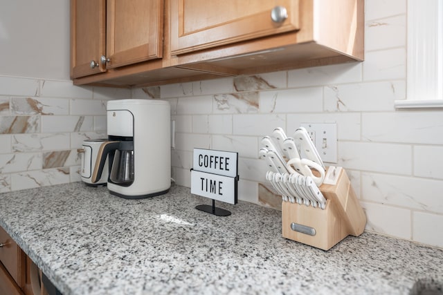 room details featuring brown cabinetry and light stone countertops