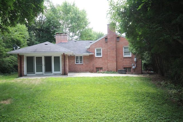 back of house with a patio, cooling unit, brick siding, a yard, and a chimney